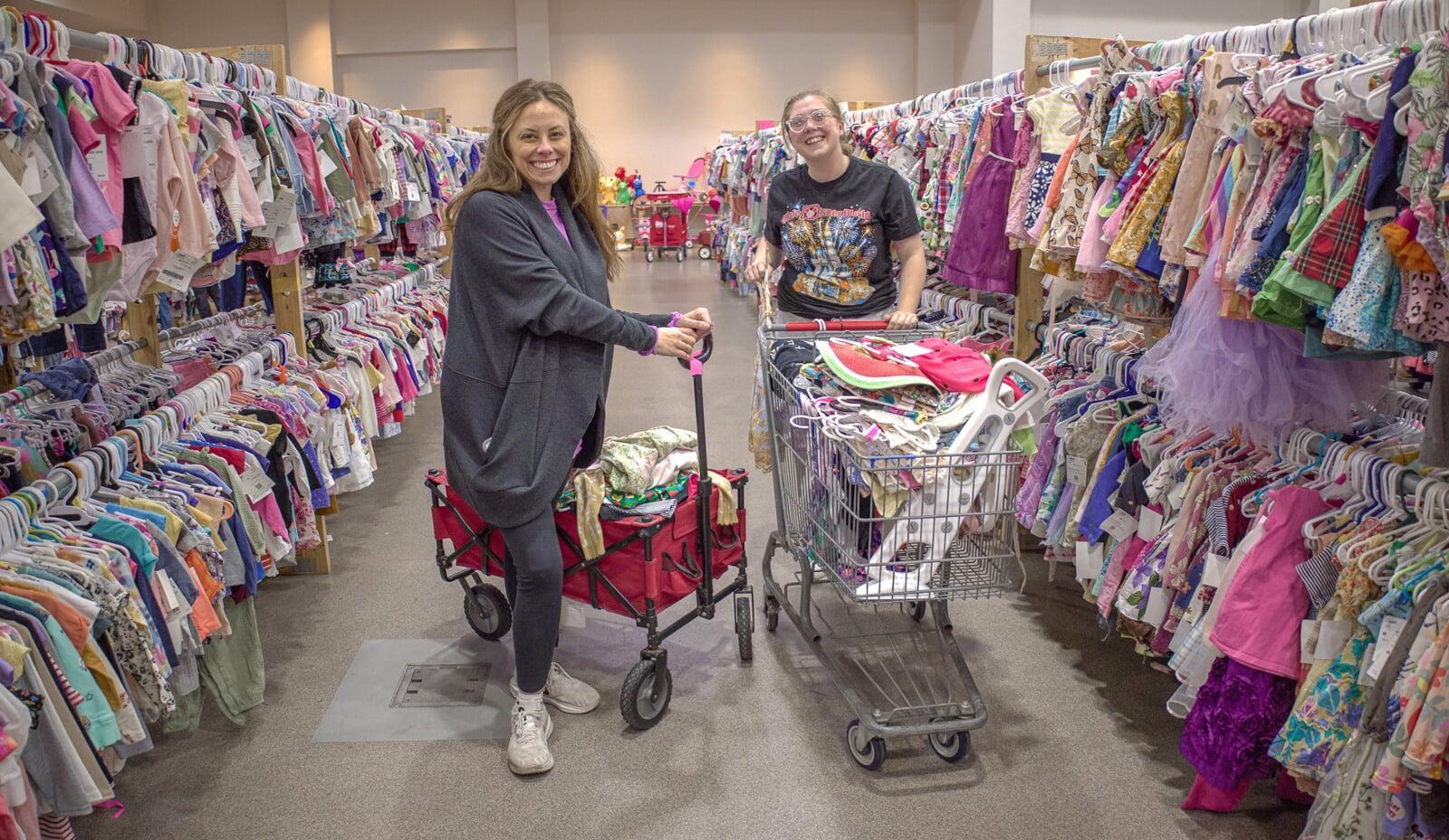 Two friends shop together—one mom wears her baby girl—as they find great deals at their local JBF sale.