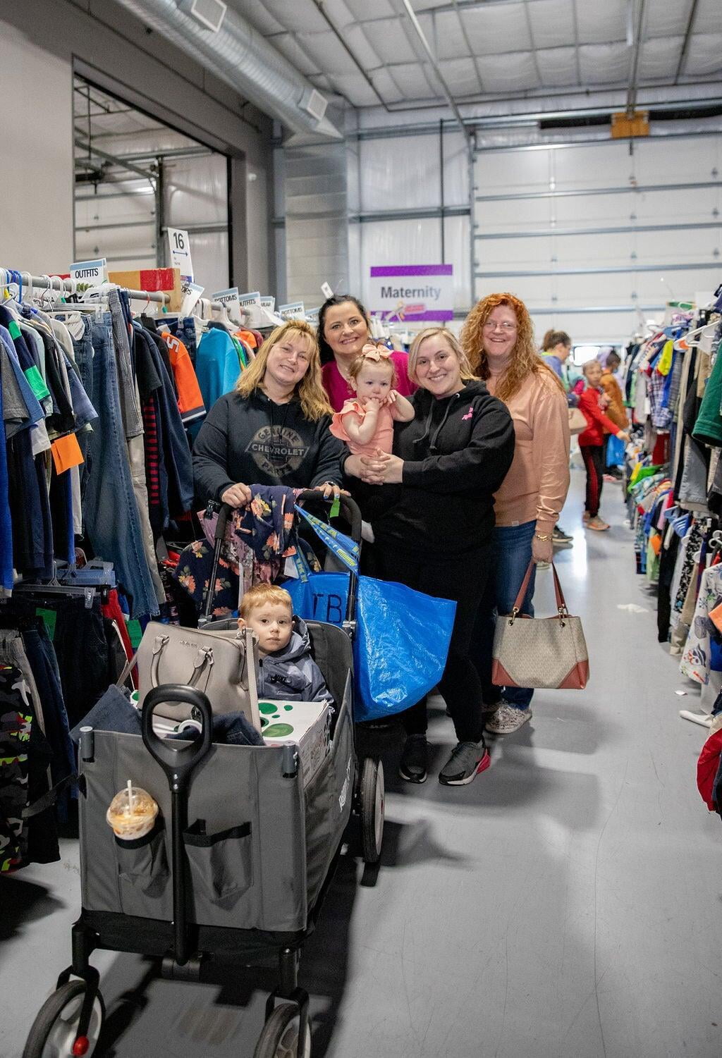 Mom and grandmother stand together, a few pieces of clothing in grandmom&#039;s hands, as they shop together for their family.