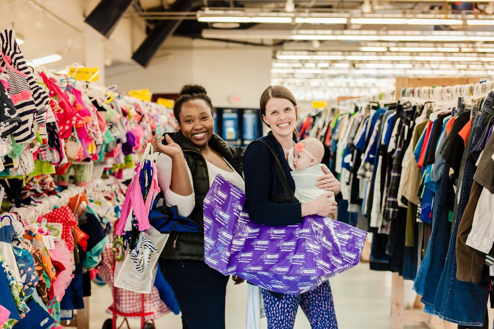 A mom and her child hug in between two rows of little girl clothes